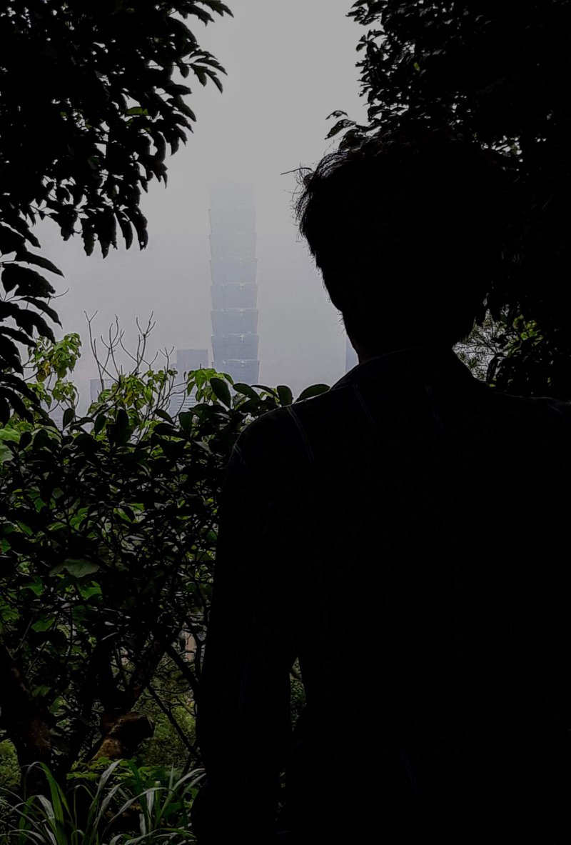 A man's silhouette. He is looking over Taipei 101.