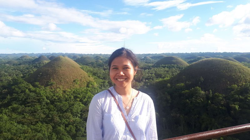 a young woman smiling, Chocolate Hills is her background